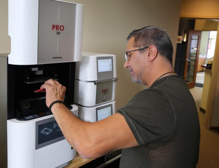 John Sanchez, Innova Dental's lead technician, operating a state-of-the-art 3D printing system for efficient and highly accurate dental fabrication.