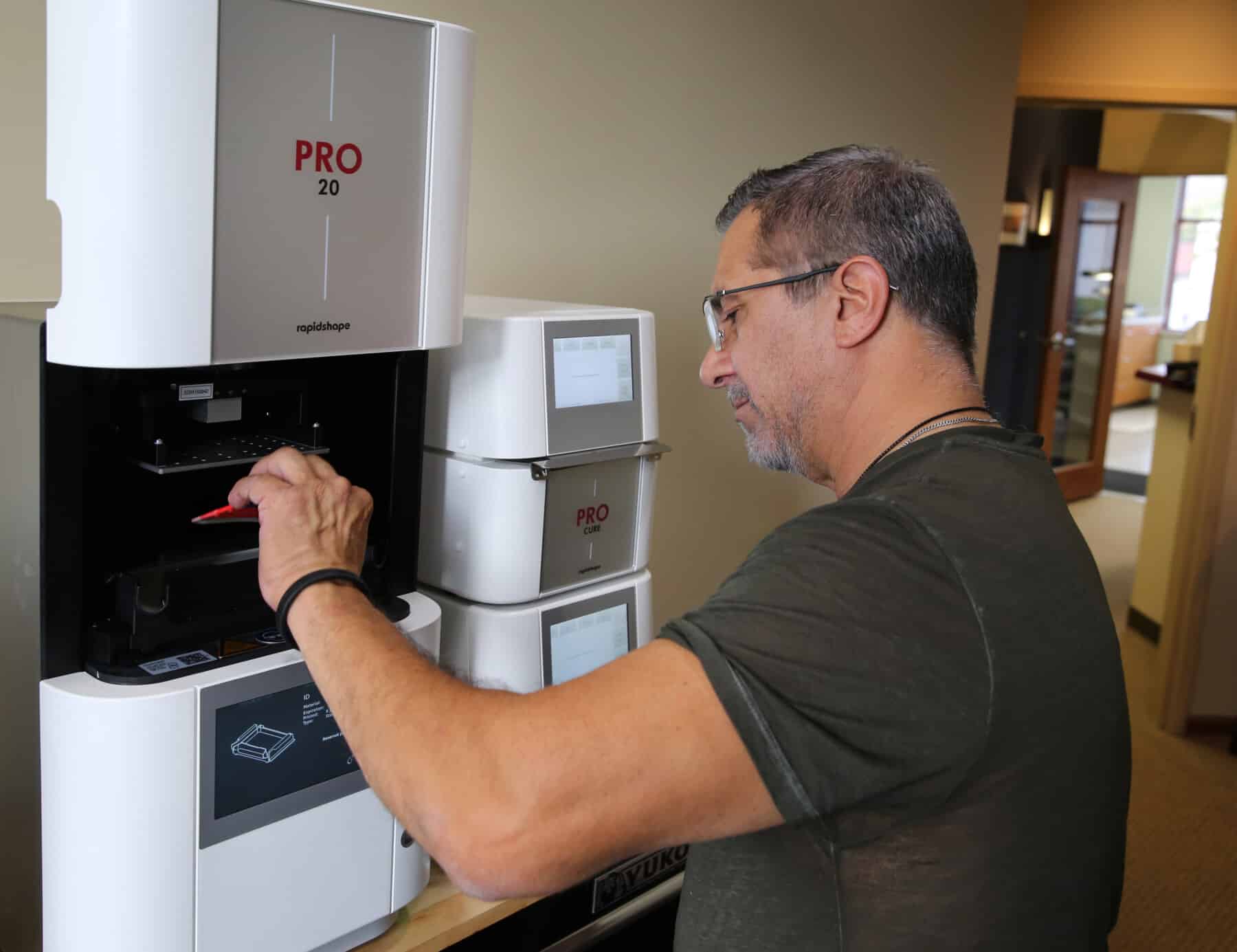 John Sanchez, Innova Dental's lead technician, operating a state-of-the-art 3D printing system for efficient and highly accurate dental fabrication.